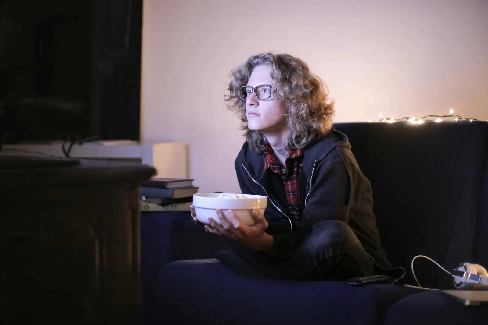 Personne pensive regardant la télévision dans une pièce à la lumière tamisée, atmosphère feutrée propice à la réflexion