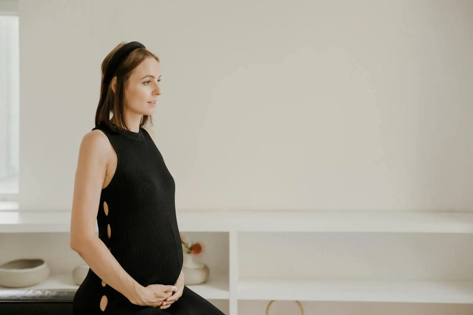 Femme enceinte souriante portant une robe de grossesse, une main posée sur son ventre arrondi
