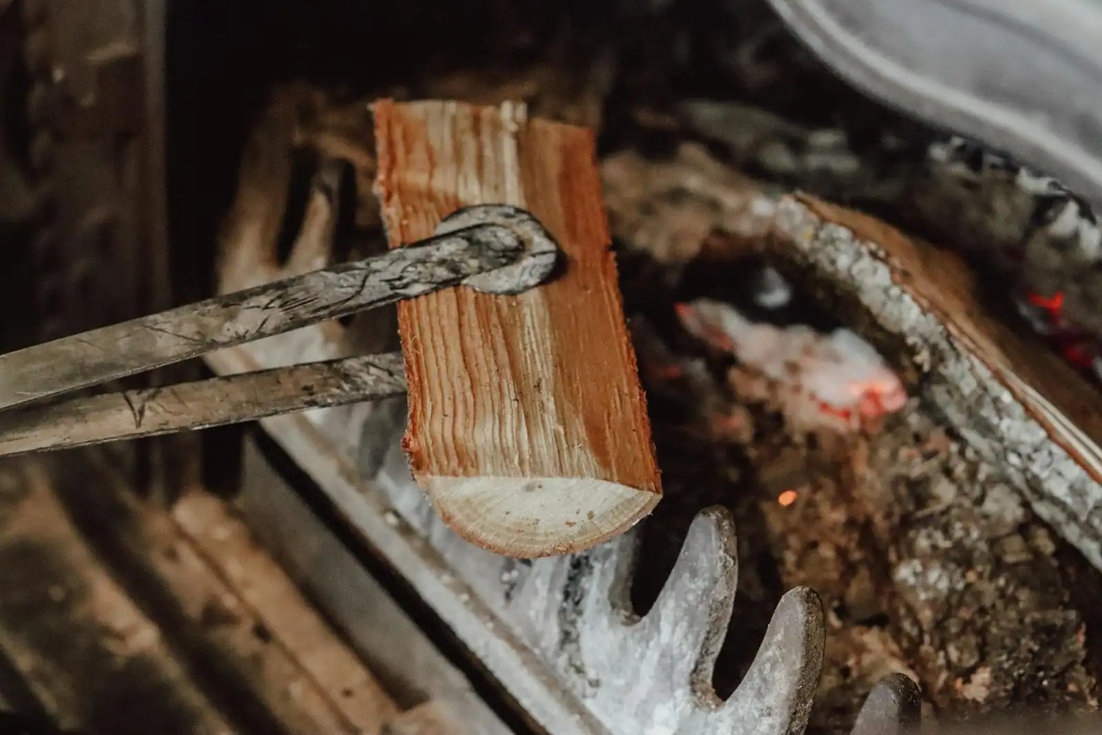 Pince à bûches saisissant une bûche au-dessus d'un foyer de cheminée