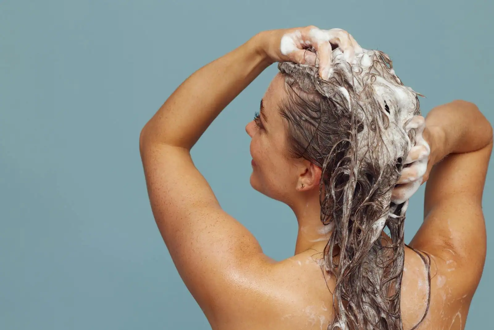 Femme se lavant les cheveux sous la douche, massage du cuir chevelu avec du shampoing