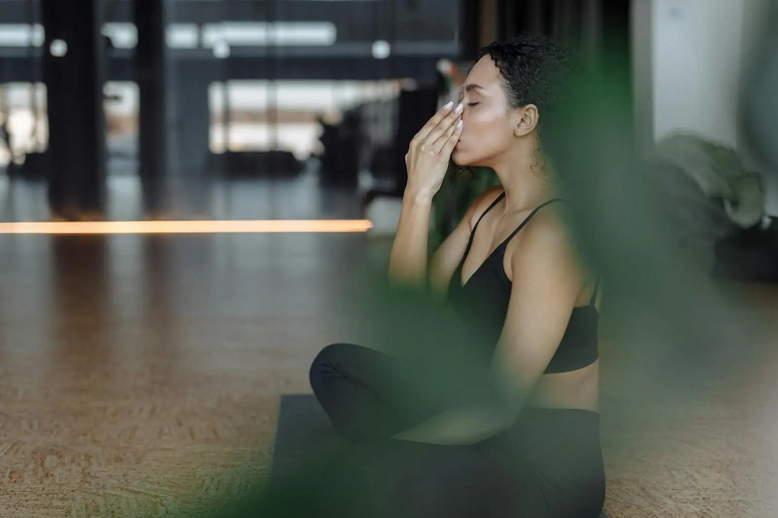 Femme en tenue de sport assise en tailleur, yeux fermés, pratiquant un exercice de respiration