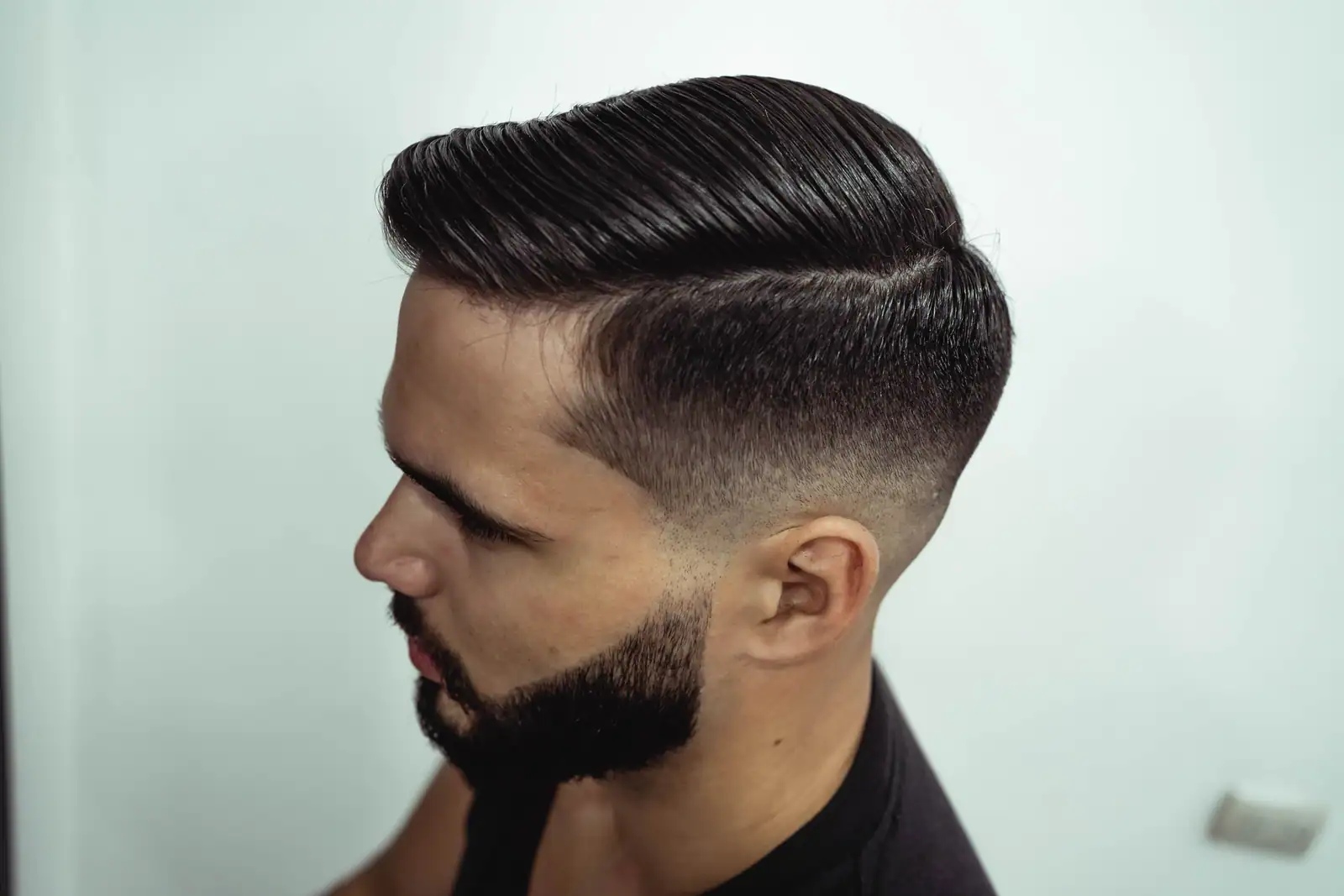 Coupe de cheveux homme vue de profil : dessus mi-long coiffé en arrière et côtés courts dégradés.