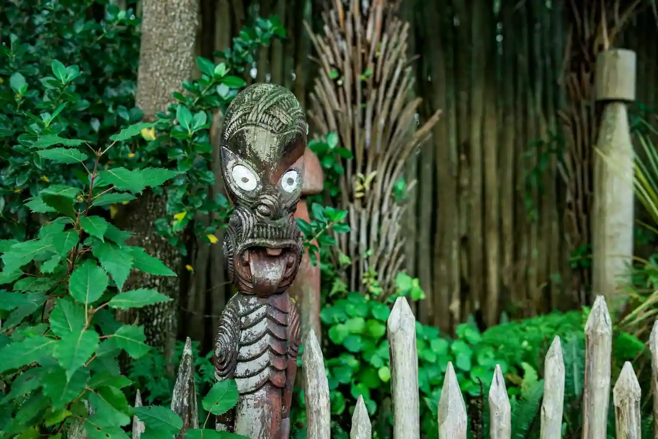 Sculpture maorie traditionnelle en bois aux yeux de nacre dans un jardin de Nouvelle-Zélande
