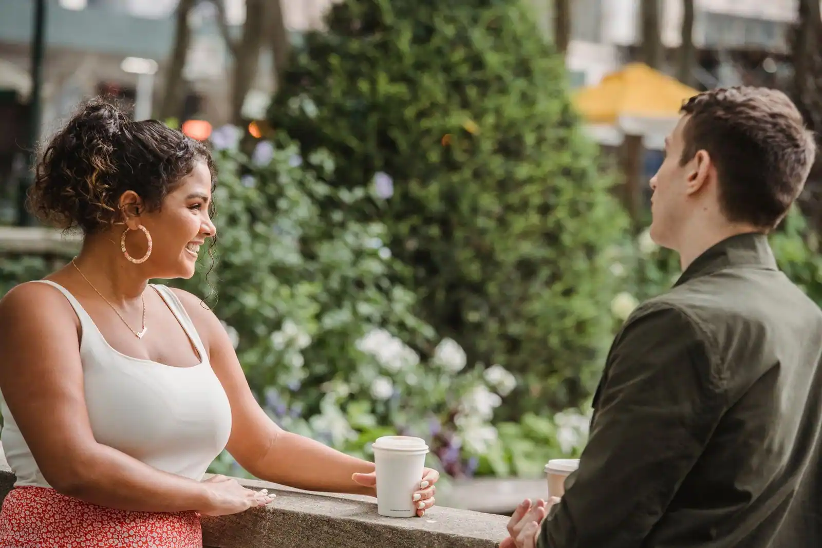 Deux personnes complices qui échangent un sourire en terrasse, ambiance de conversation détendue