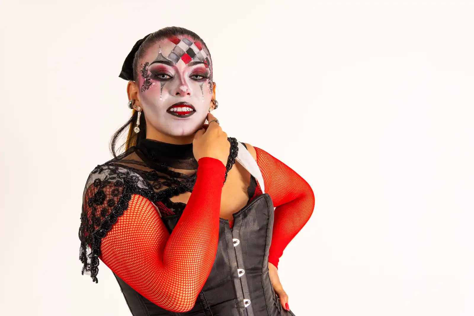 Femme au maquillage de style arlequin, visage blanc orné de losanges rouges et noirs, dans l'esprit du look comic