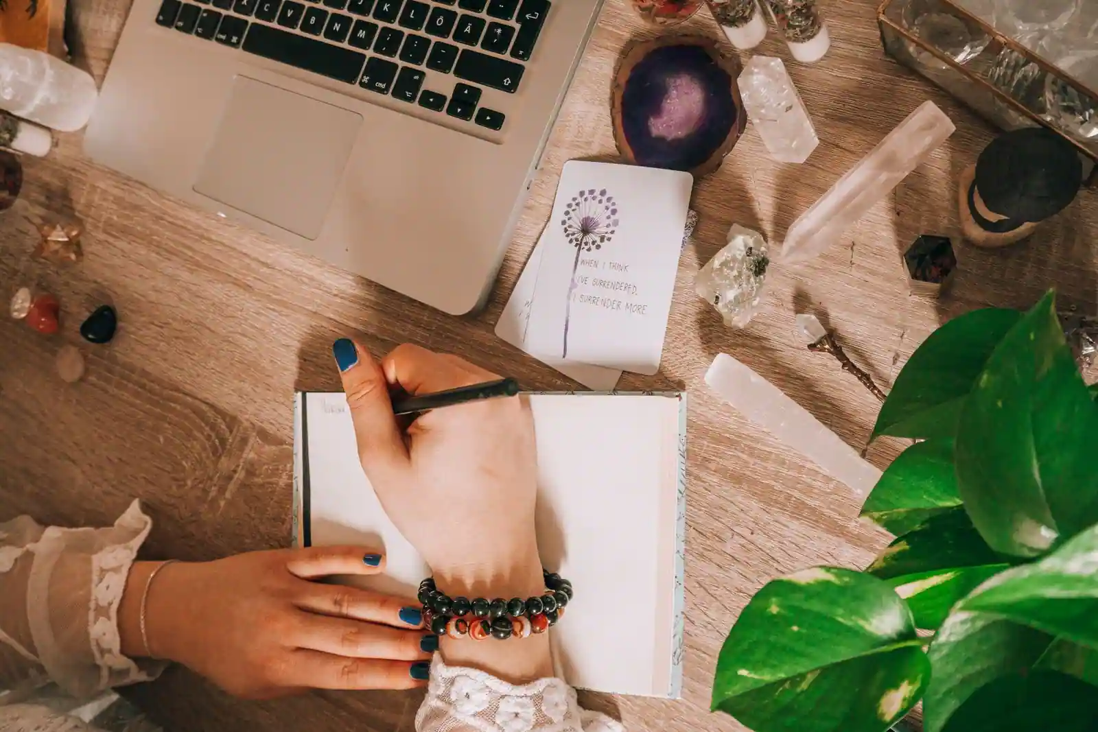 Personne écrivant dans un carnet sur un bureau en bois, scène d'introspection et de réflexion.