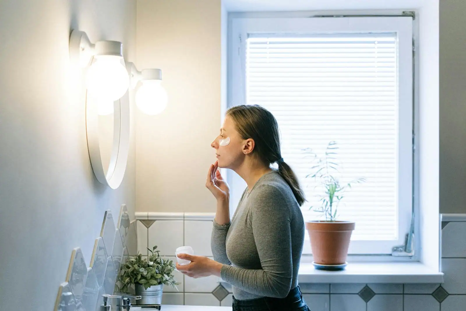 Femme appliquant une crème de soin sur son visage, geste d'une routine de beauté quotidienne.