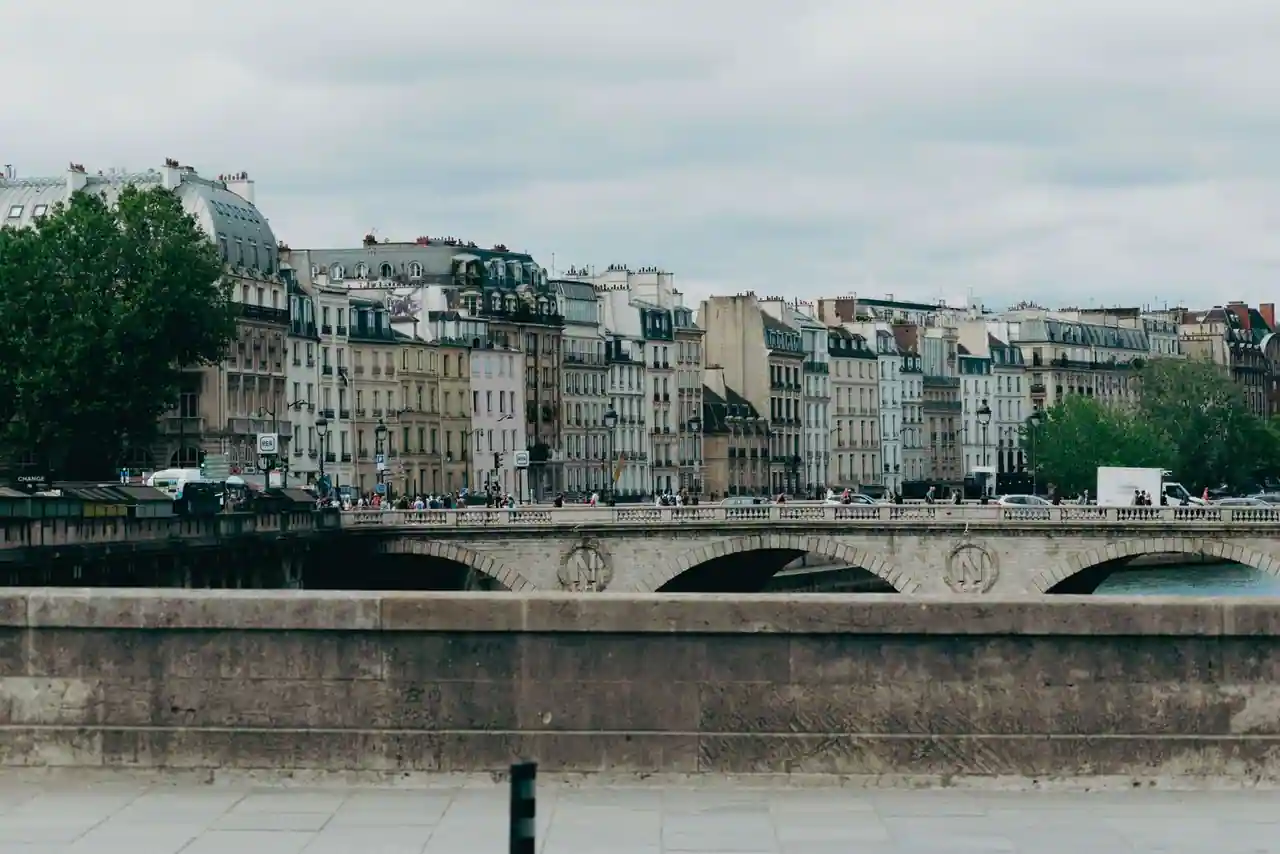 Vue de Paris au bord de la Seine, ponts et toits haussmanniens sous la lumière du jour.