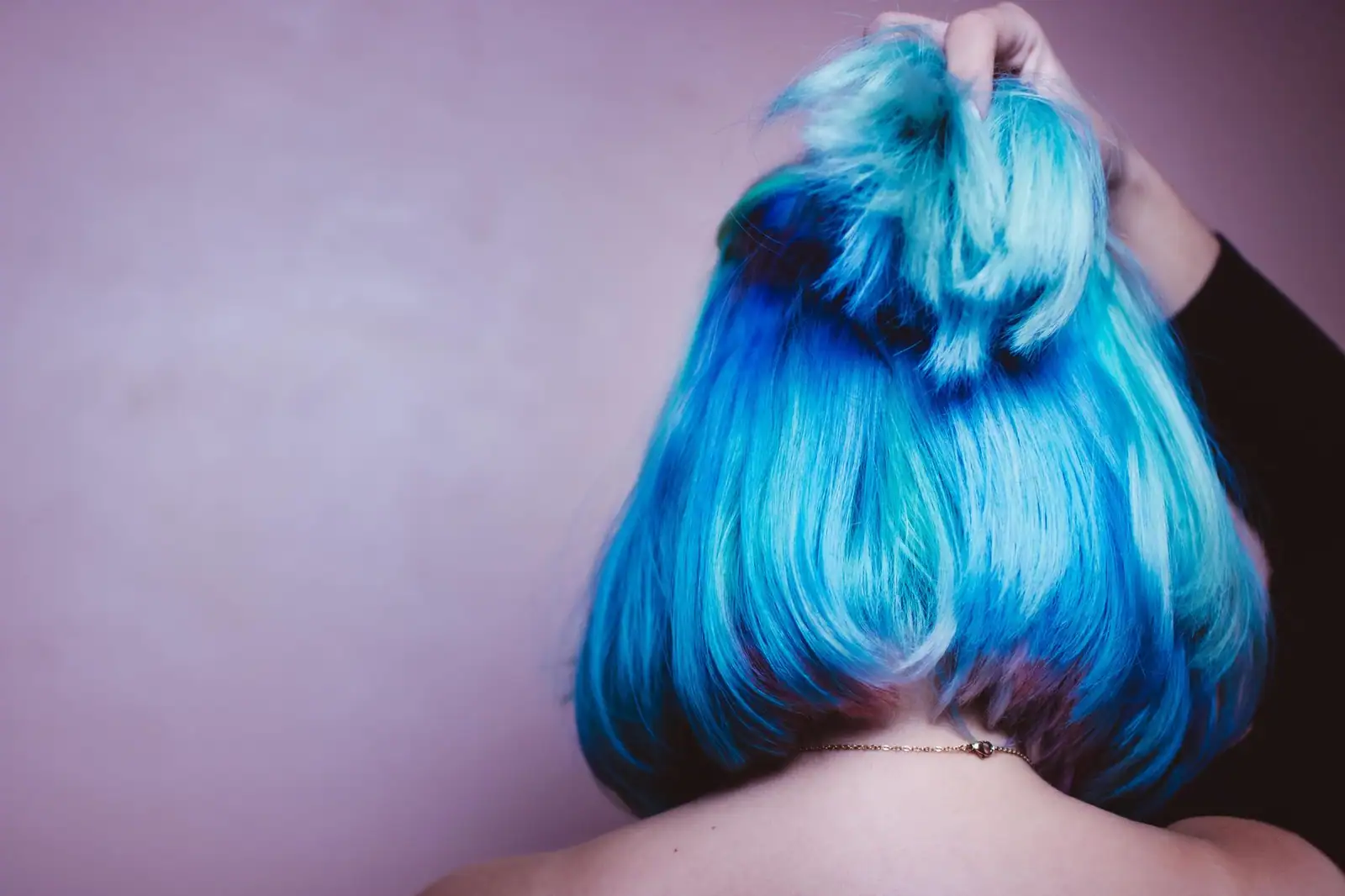 Chevelure teinte en bleu vue de dos, mèches turquoise et bleu profond relevées à la main