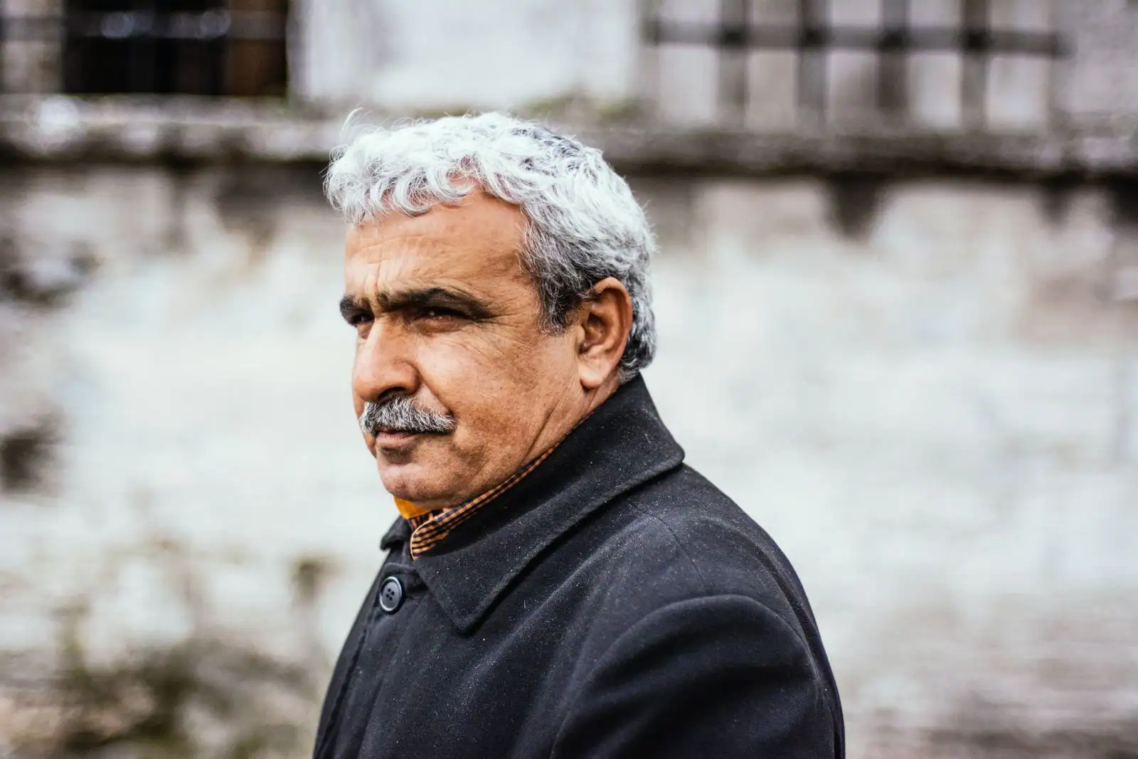 Portrait en extérieur d'un homme aux cheveux poivre et sel et à la moustache grise.