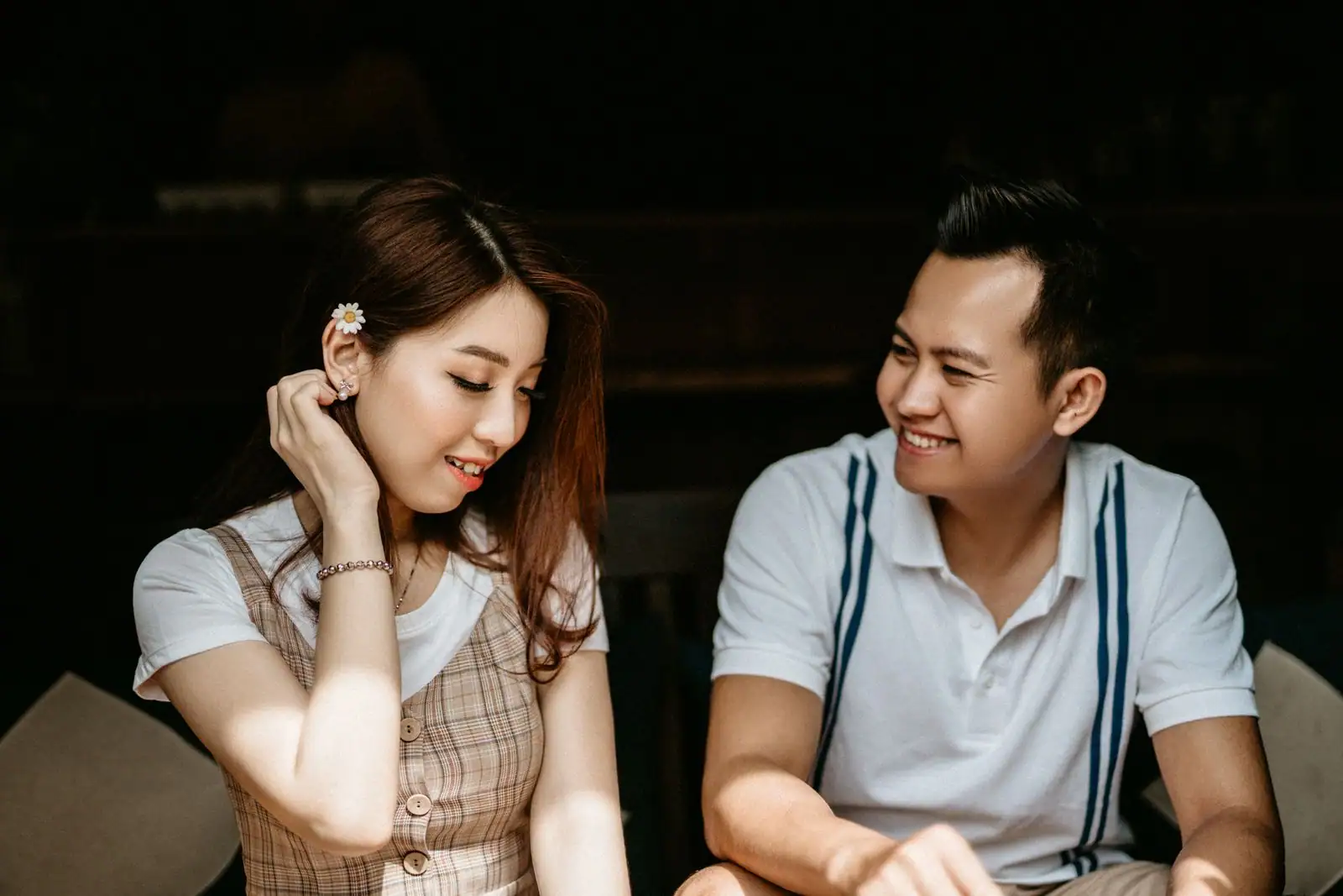 Un homme et une femme assis côte à côte, souriants, échangeant un regard complice en intérieur