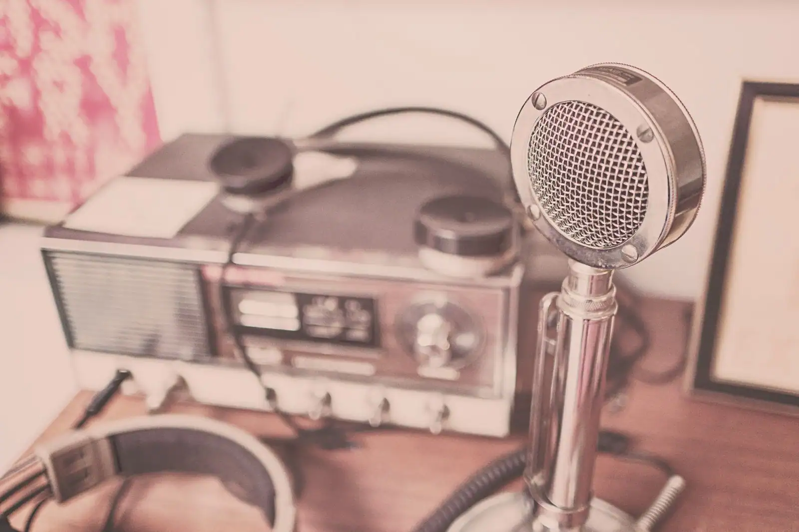 Un poste de radio vintage, un micro de studio chromé et un casque audio posés sur une table en bois