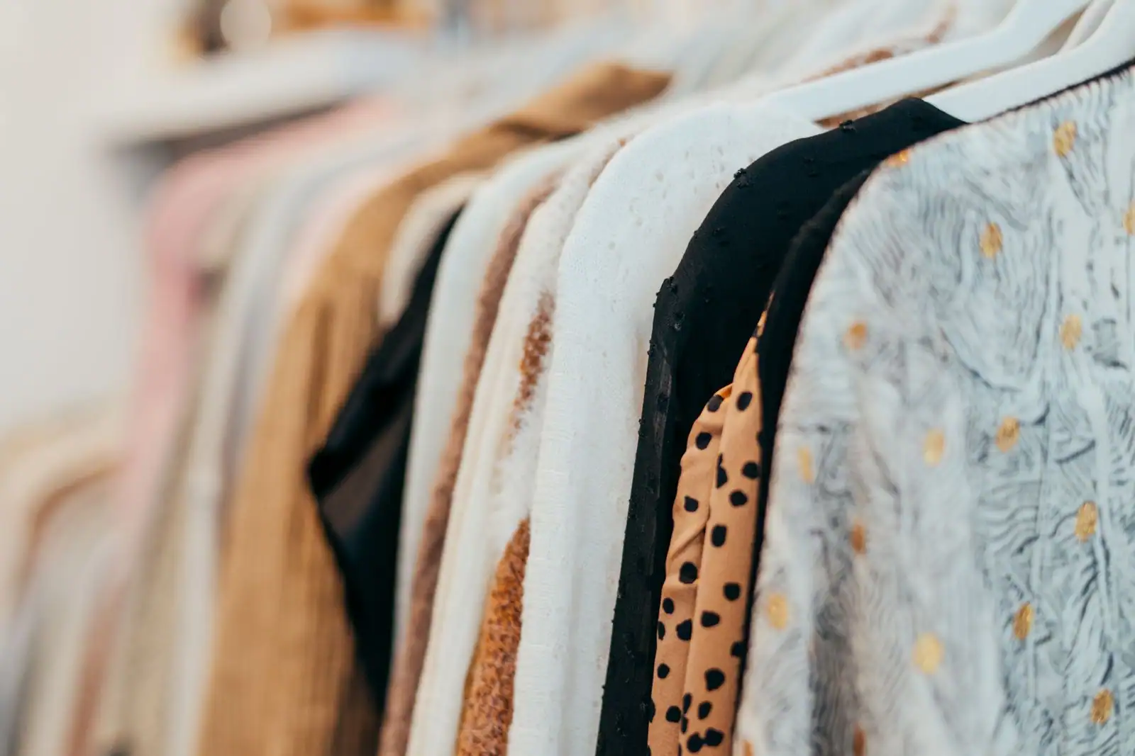 Vêtements variés suspendus sur des cintres à un portant de boutique de mode