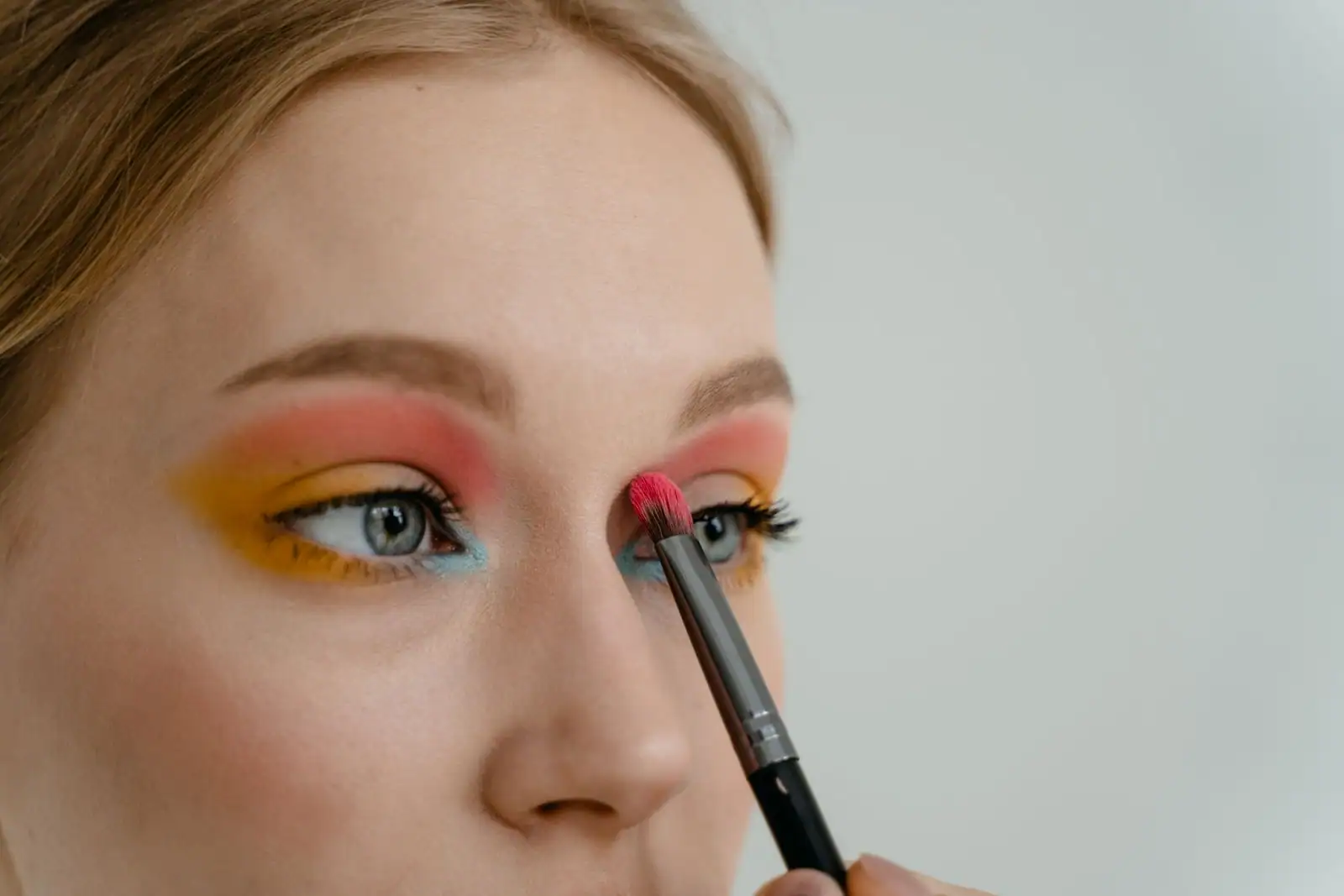 Application d'un fard à paupières coloré au pinceau sur la paupière, en gros plan.