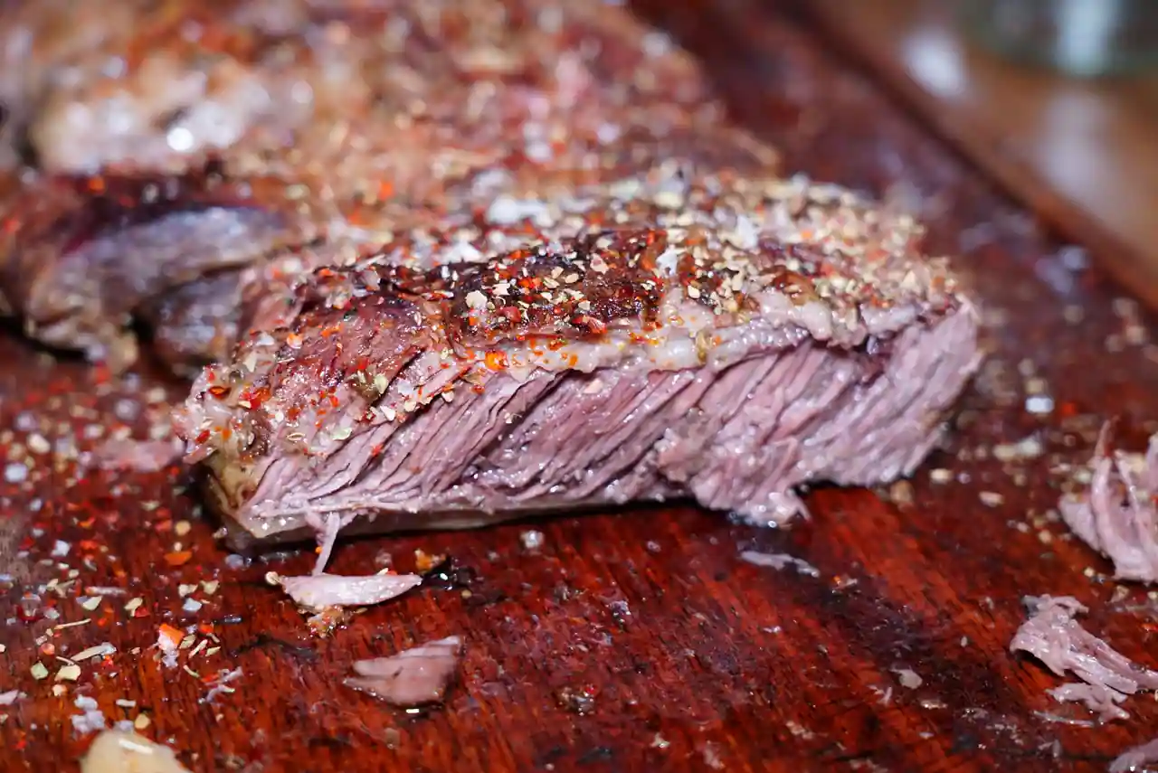 Pièce de bœuf grillée et tranchée sur une planche en bois, laissant voir un cœur rosé pâle