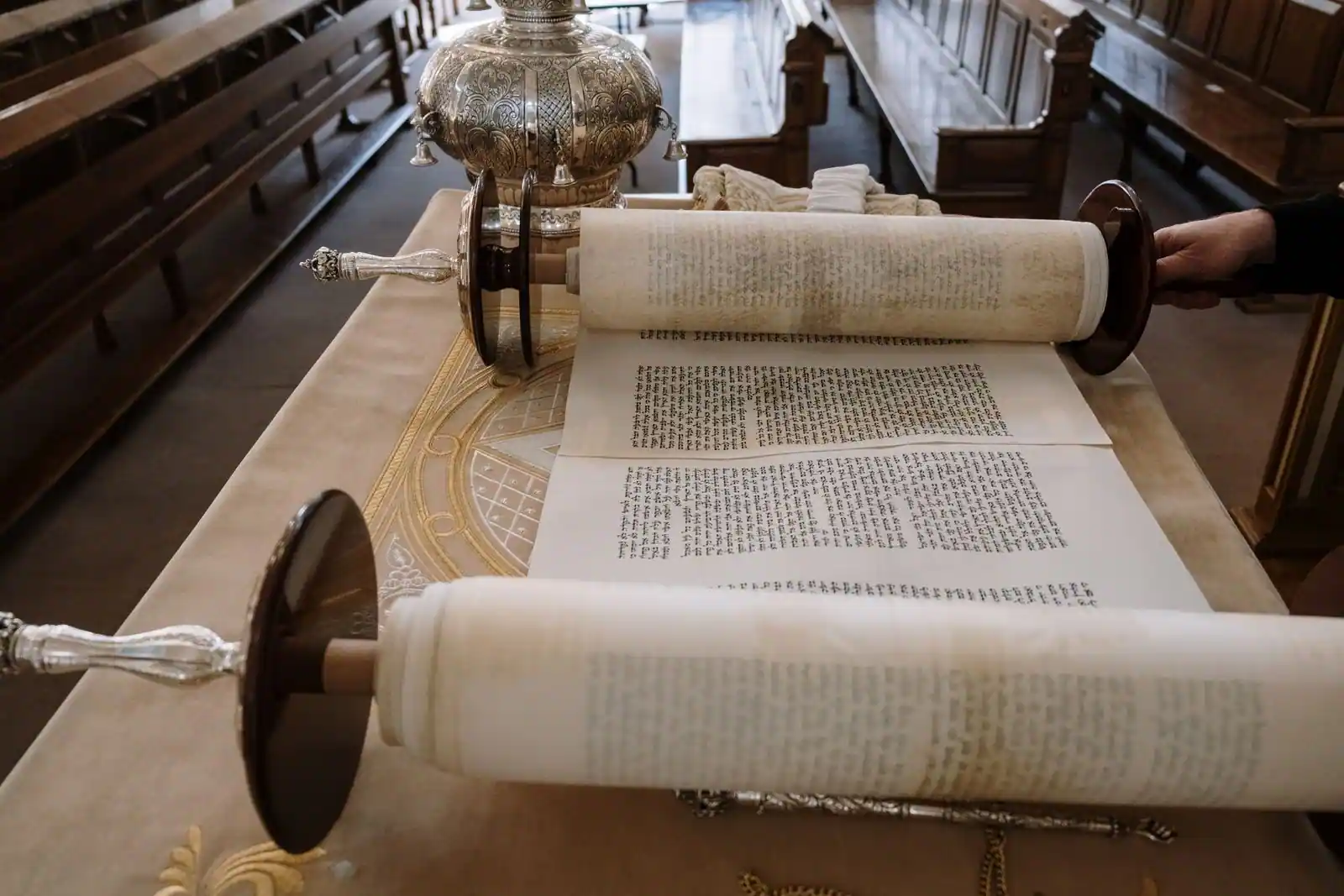 Rouleau de la Torah déroulé sur une table de lecture, texte hébraïque manuscrit sur parchemin, dans une synagogue.
