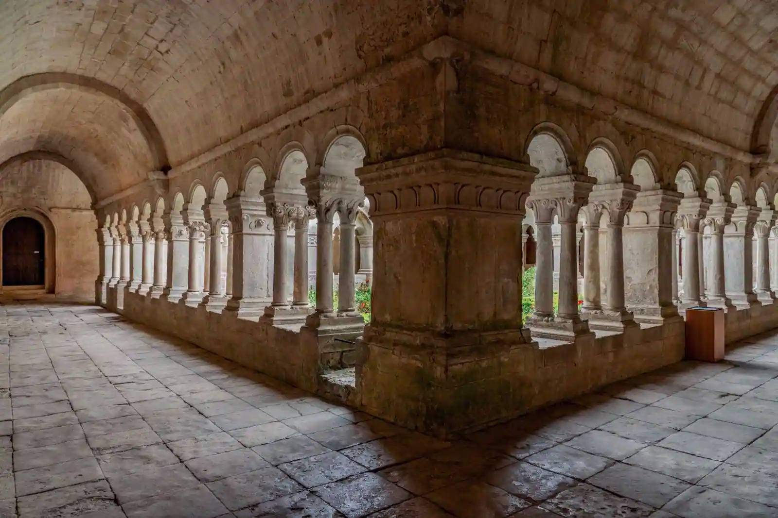 Galerie voûtée d'un cloître de monastère, aux arcades de pierre ouvrant sur la cour intérieure