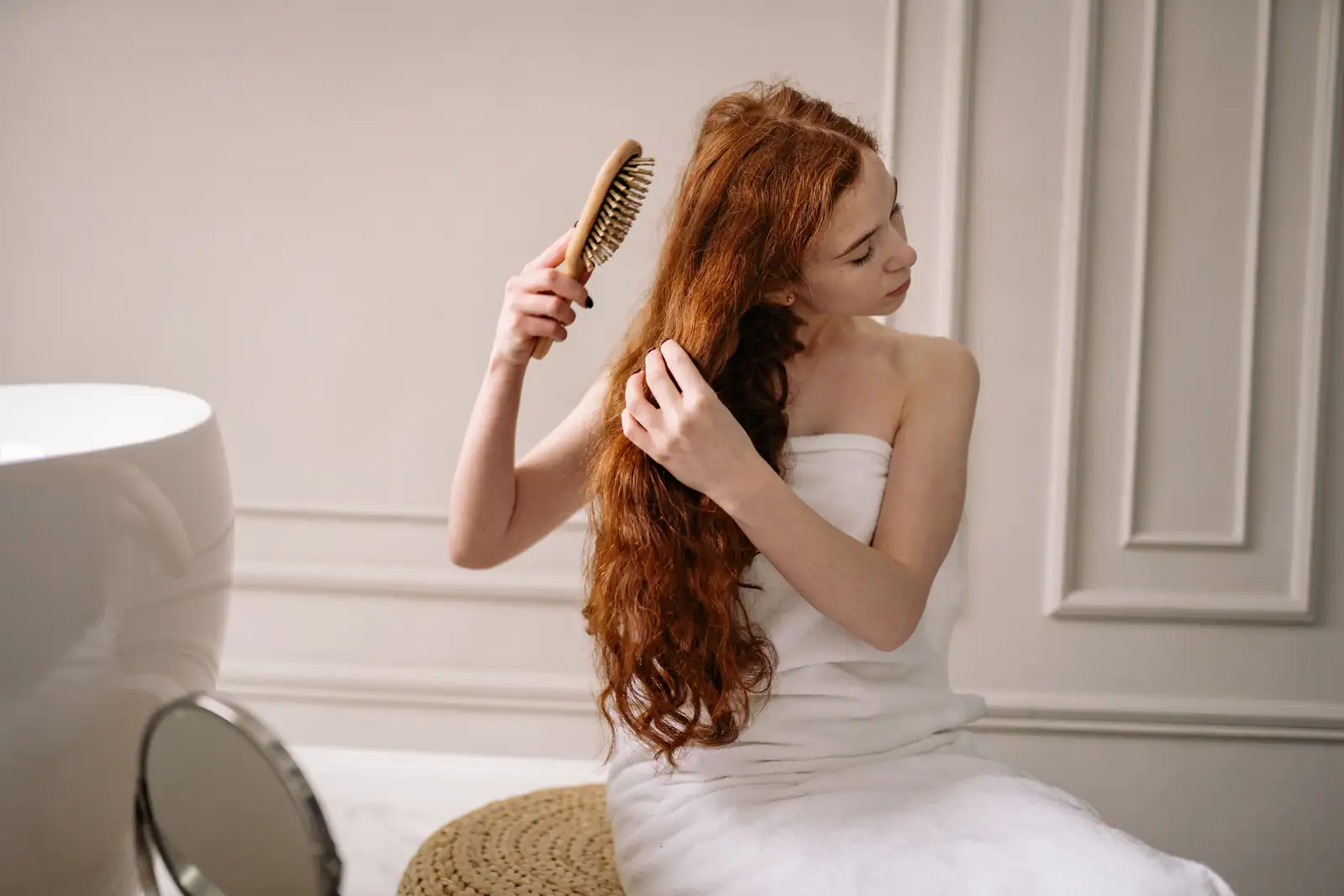 Femme brossant délicatement ses cheveux longs et sains, geste de routine capillaire.