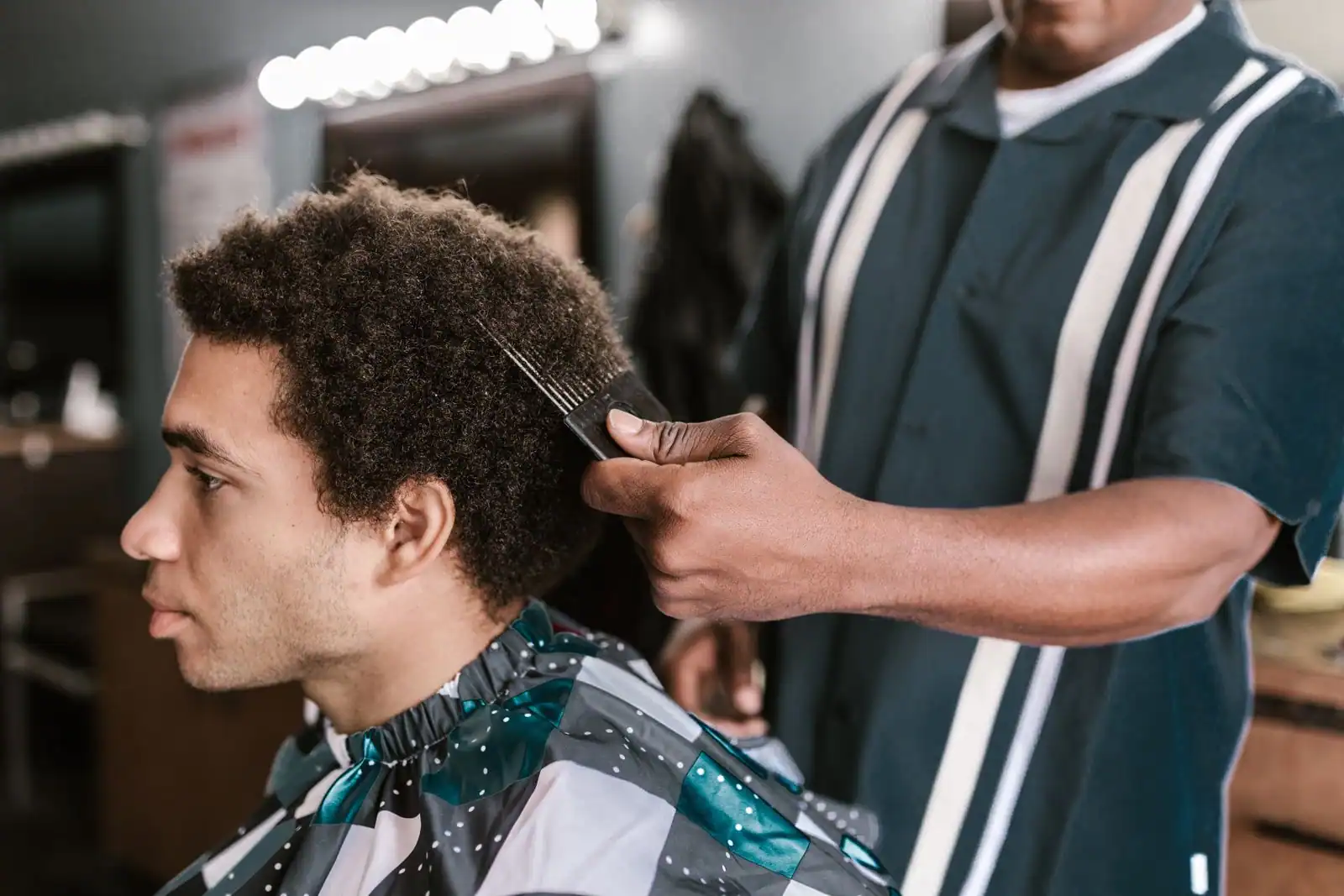 Client dans un salon de coiffure pendant une coupe dégradée réalisée par un barbier.