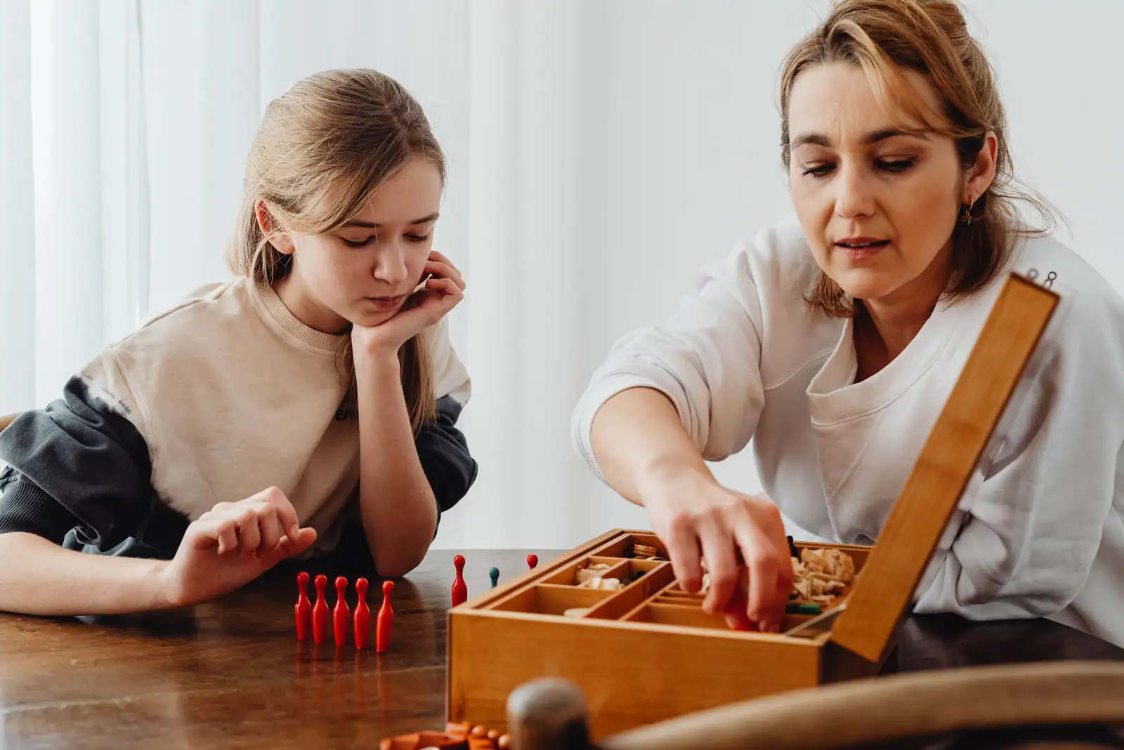 Mère et fille installent les pièces d'un jeu de société en bois sur la table du salon.