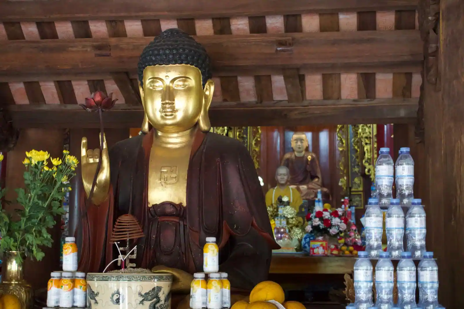 Statue dorée de Bouddha entourée d'offrandes dans une pagode vietnamienne